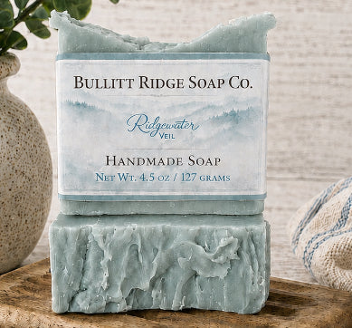 Two bars of handmade soap from Bullitt Ridge Soap Co. on a wooden surface with a neutral background.