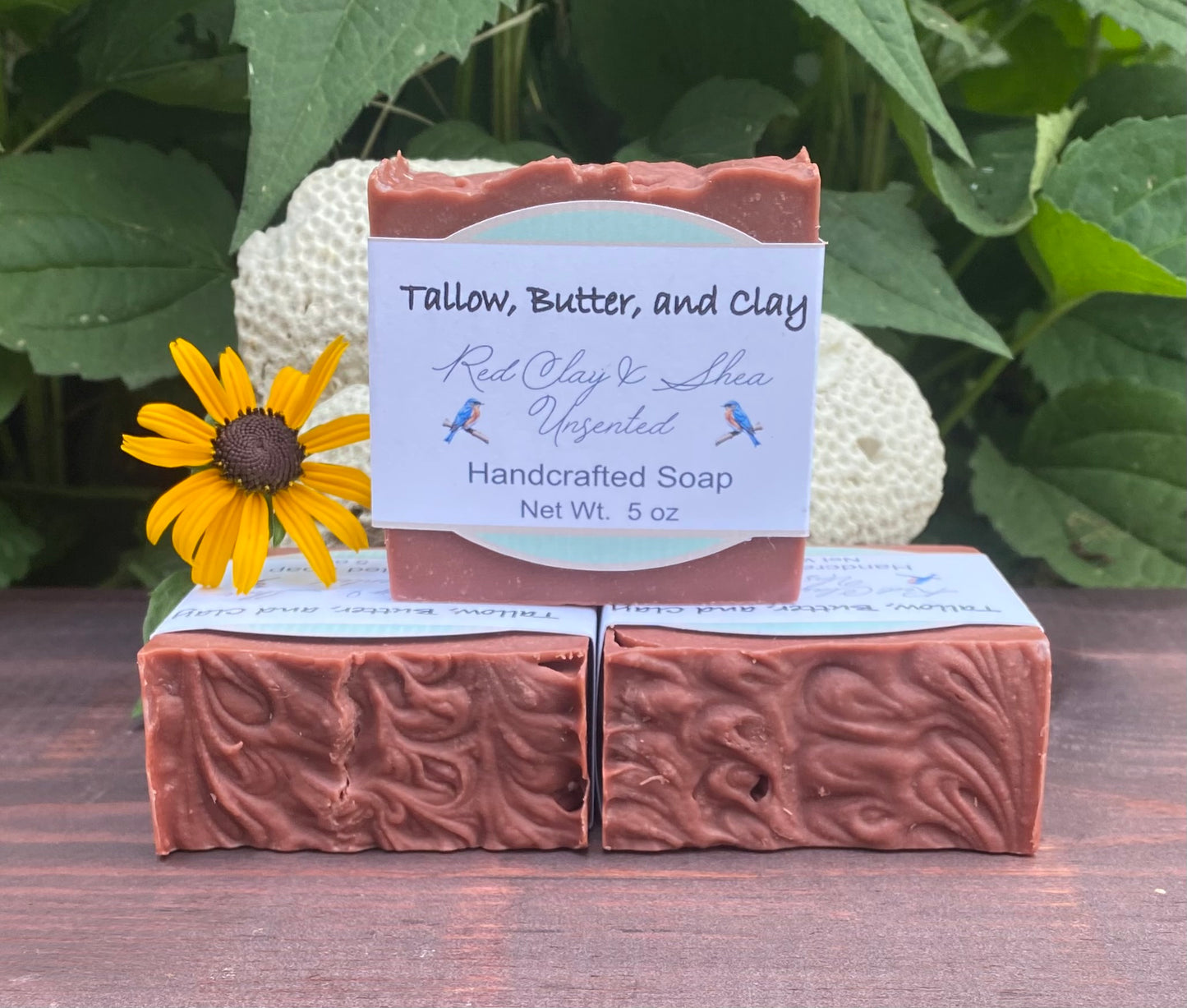 “Moroccan red clay tallow soap with deep red color and intricate swirls, displayed with greenery, made with tallow, shea butter, olive oil, and castor oil.”